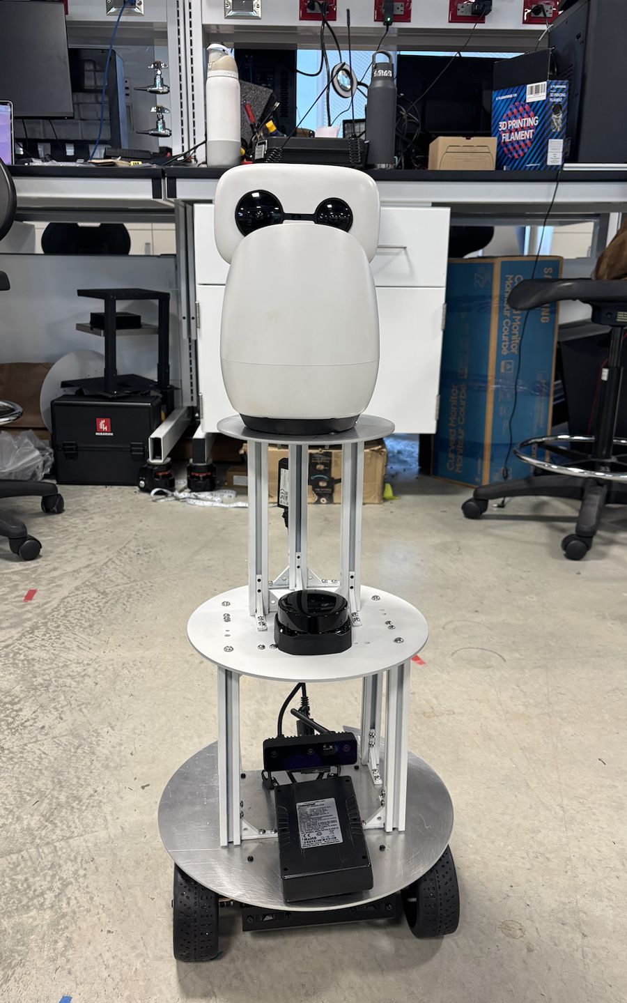 The assembled Tourguide robot: a white Reachy Mini head on an aluminum tower above a four-wheeled ROSbot base